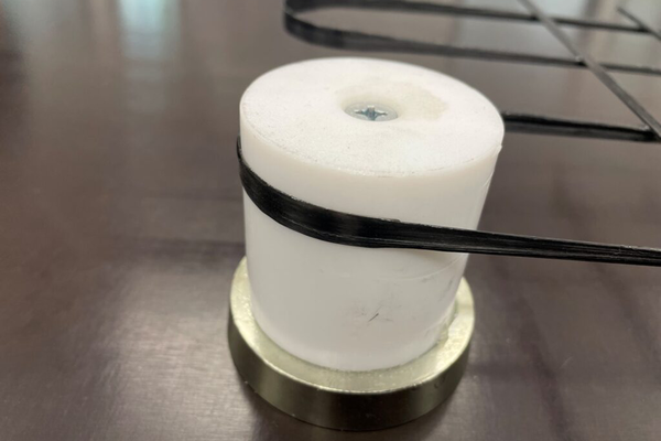 Nahaufnahme einer weißfarbenen Rolle um welche schwarzes Garn gelenkt wird/bei Verlinkung führt der Link zur Projektwebsite